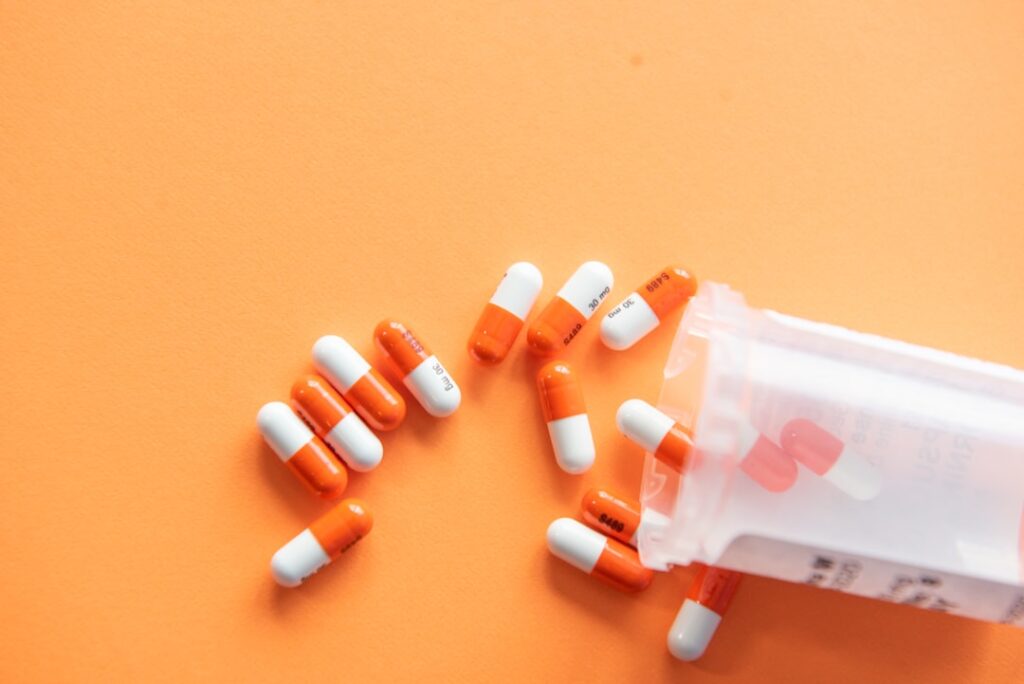 A pharmacy staff member helps a patient review medication options and paperwork at a counter.