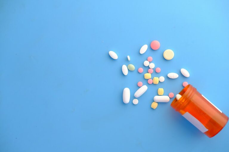 A resident reviews a prescription receipt and insurance documents beside a medication bottle and calculator.