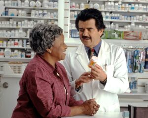 Patient reviews an insurance letter beside a prescription bottle and paperwork on a kitchen table.