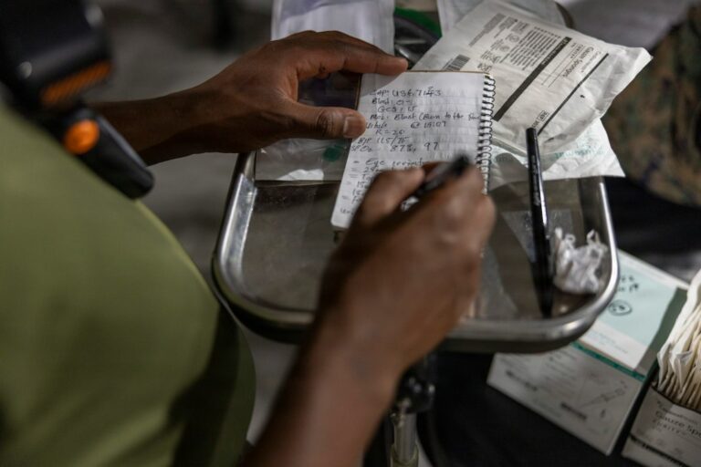Person comparing a pharmacy receipt, prescription bottle, and insurance statement at a kitchen table.